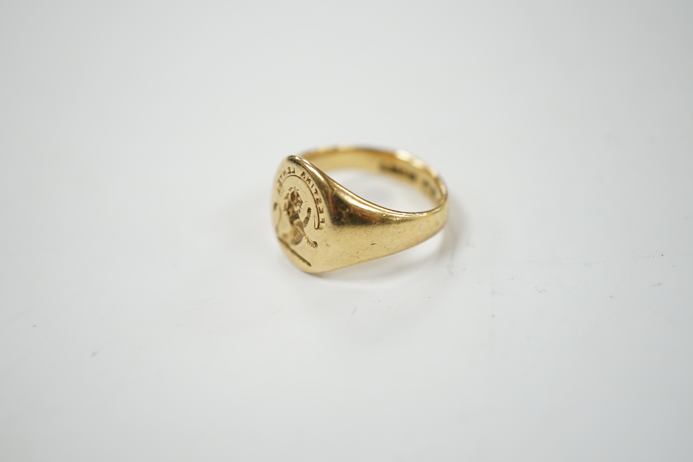 A George V 18ct gold signet intaglio ring, carved with family crest and motto, size K, 9 grams.